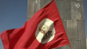 Foto van een rode vlag met portret van een man in witte cirkel erop.