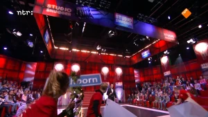 Foto van de studio van Snugger waar veel publiek zit en beetje in de verte zie je de presentator op het podium.