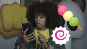 Foto van presentator/vrouw met smartphone/mobieltje in haar hand, erbij getekend een soort lolly met drie bolletjes en een symbooltje: emoticons.