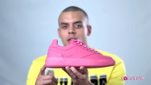 Foto van presentator die een roze schoen vasthoudt.