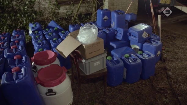 Foto van aantal jerrycans, dozen en plastic vaten die op de grond staan bij elkaar.