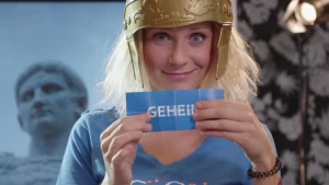 Foto van vrouw, portret, met plastic helm op die papiertje vasthoudt met "geheim" erop.