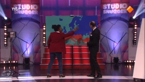 Foto van presentator en vrouw samen in de studio van Snugger die wijzen naar een kaart van Europa aan de muur.