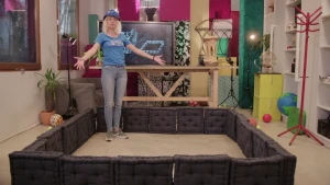 Foto van presentator in kamer die staat in een vierkant laag fort gemaakt van 20 kussens.