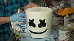 Foto van iemand die bezig is met een grote pot met apart gezichtje erin in atelier.