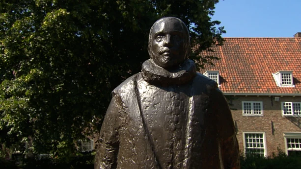 Foto van een beeld van Willem van Oranje met op de achtergrond oude huizen.