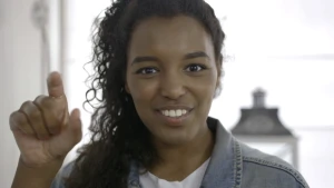 Foto van presentator, je ziet alleen haar hoofd, die met één hand een gebaar laat zien.