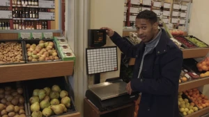 Foto van man in supermarkt bij een weegschaal die hij controleert.