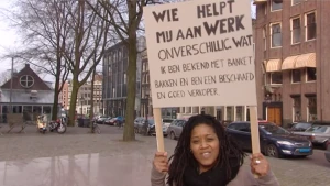 Foto van een vrouw op een stadsplein die een protestbord vasthoudt.