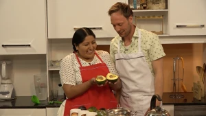 Foto van man en vrouw voor het fornuis in een keuken, de vrouw houdt een avocado vast.