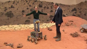 Foto van man en vrouw in een decor van een maanlandschap, de vrouw staat op een rijdend maankarretje.