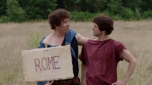 Foto van twee mannen verkleed als Romein, een ervan houdt een bord met Rome erop vast.