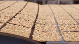 Een foto van een metalen, rond gedeelte links en een lopende band rechts. Van de lopende band vallen rechthoekige crackers met zaadjes van een lichte kleur erop op het metalen deel links, dat iets omhoog loopt of rolt naar een niet-zichtbaar gedeelte.