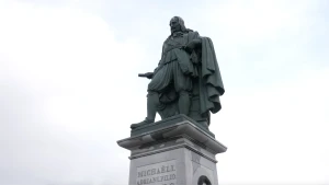 Een foto van een beeld met een groenachtige kleur van de Nederlandse zeeheld Michiel de Ruyter dat in zijn geboorteplaats Vlissingen staat. Hij draagt een pak en een cape om zijn nek. In zijn rechterhand heeft hij een verrekijker vast.