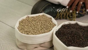 Een foto van twee witte stoffen mandjes met daarin groene en zwarte peper. Ze staan op een grijswitte vloer. De schoen en een stukje van de hand van presentator Eva die erachter zit zijn te zien. Het mandje witte peper dat voor Eva staat is niet te zien.