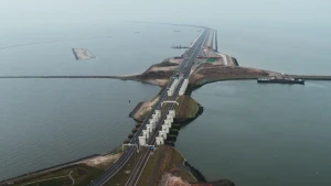 Een foto van de Afsluitdijk. Dit is een grote dijk, met hierover een dubbele snelweg. Aan allebei de kanten zie je water.