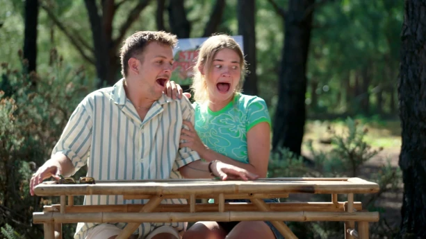Een foto van Jurre en Emma die buiten zitten aan een houten tafel. Ze schrikken allebei heel erg, maar je ziet niet waarom.