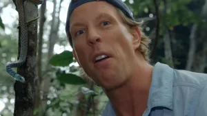 Een foto van het gezicht van presentator Freek. Op de de achtergrond hangt er een slang aan een boom.