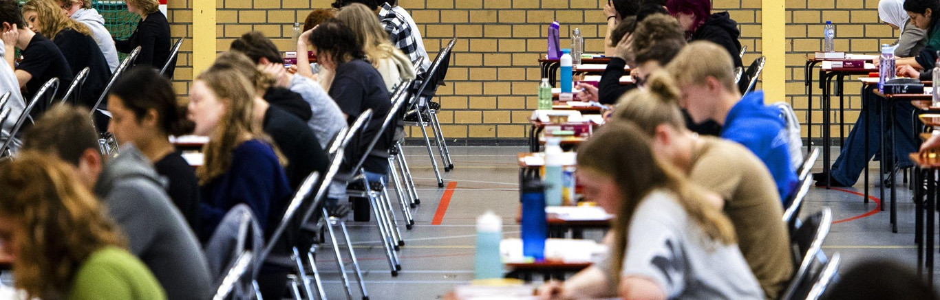 Examenleerlingen in gymzaal aan tafeltjes