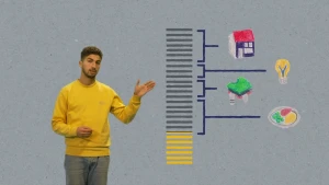 Een foto van een presentator die een overzicht aanwijst over te besteden geld. Twintig grijze balkjes zijn verbonden met plaatjes van een huis, een gloeilamp, kleding en een bord met eten. Zeven gele balkjes tonen het geld dat nog uitgegeven kan worden.