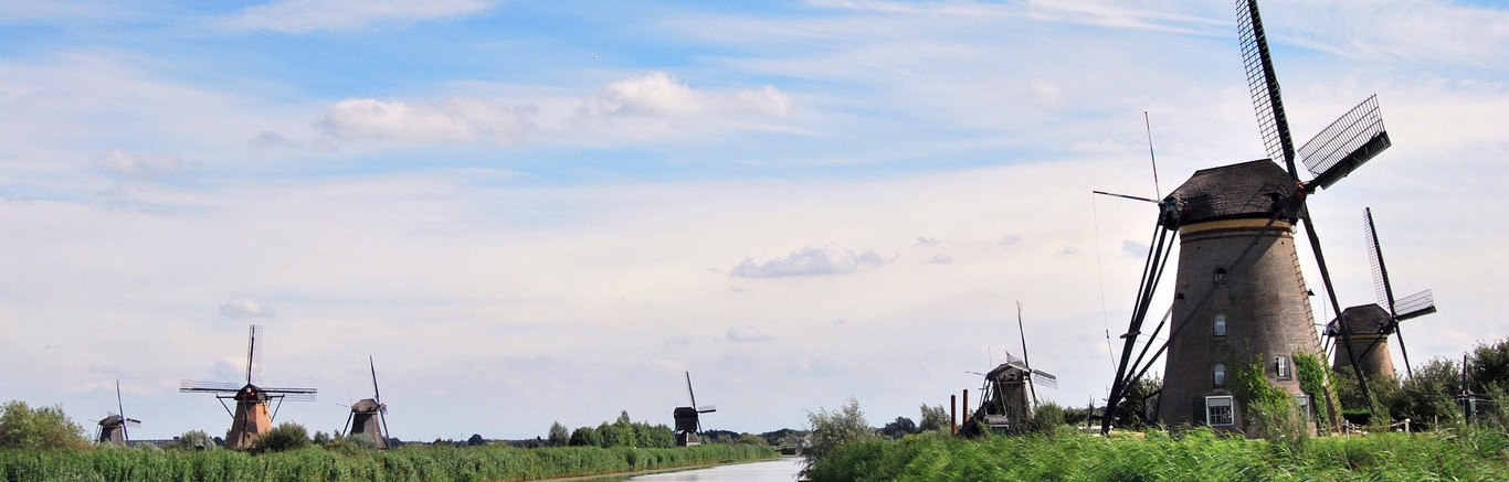 Zeven molens bij Kinderdijk aan het water, blauwe lucht met sluierbewolking