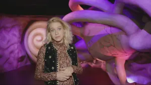 Een foto van presentator Janouk die in een ruimte staat van het 'Reis door de mens' museum.