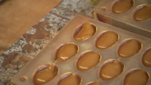 Een foto van een vorm om paaseitjes te maken. In de vorm zit chocolade en karamelvulling.