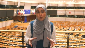 Een foto van een presentator op de tribune in de zaal van het Europees Parlement in Brussel.