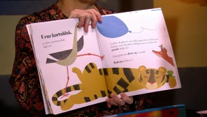 Een foto van jeugdbibliothecaris Toos die een anderstalig boek open houdt. Het boek is in het Turk geschreven en niet in het Nederlands. Het gezicht van Toos is niet zichtbaar op de foto.