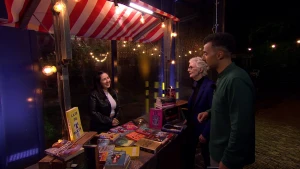 Een foto van Dilayra die achter een kraam vol met boeken staat met booktokboeken.  Booktokboeken zijn boeken die via social media zoals TikTok viraal zijn gegaan. Presentator Özcan Akyol en schrijfster Carry Slee staan voor de kraam.