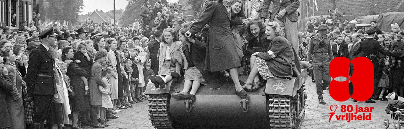 Zwart-witfoto van blije mensen op straat en op een tank.