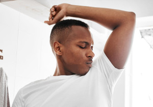 Jongen in wit T-shirt ruikt aan zijn eigen oksel.