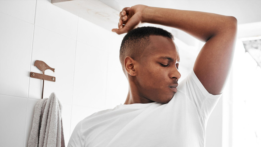 Jongen in wit T-shirt ruikt aan zijn eigen oksel.