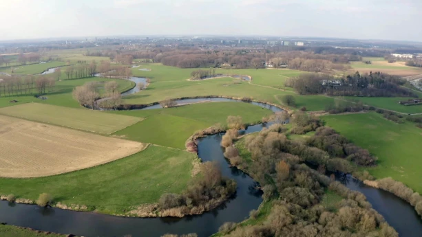 Een foto van een rivier die in een kronkelende vorm door een landschap loopt. In de rivier vormt zich ook een meander, een lus in de loop van de rivier.