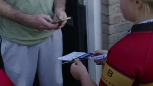 Man scant een blaadje van de Grote Clubactie met zijn telefoon