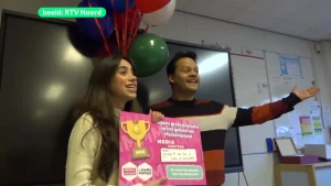 Man en vrouw staan met bord van MediaMasters en ballonnen op de achtergrond.