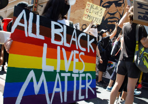 Demonstratie voor Black lives matter, in witte letters op regenboogbord.