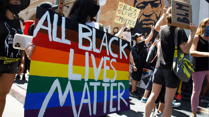 Demonstratie voor Black lives matter, in witte letters op regenboogbord.