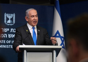 Premier Netanyahu achter spreekgestoelte met Israelische vlag achter hem.