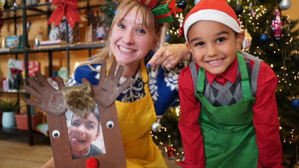 Een foto van de presentatrice en kind met ekrstmuts op met geknutseld rendierfotolijstje