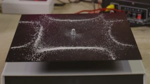 Foto van zwarte stalen plaat met witte zoutkorrels in een vierkant patroon met buigende lijnen.