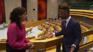 Op deze afbeelding staan een vrouw en een man op het balkon van de Tweede Kamer. Ze staan tegenover elkaar en zijn met elkaar in gesprek.