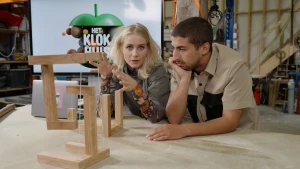 Foto van presentatoren Nizar en Janouk met een zelfgemaakt zwevend kunstwerk, gemaakt van houten latjes en draadjes.