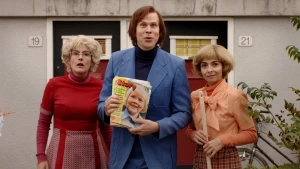 Foto van man met de eerste Story in zijn hand, met naast hem twee vrouwen gekleed in jaren 70-kleding.