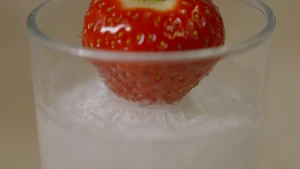 Foto van aardbei in een glas met bevroren vloeistof.