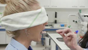 Een foto van presentator Janouk die geblinddoekt is. Een hand steekt een lepel ijs in haar mond.