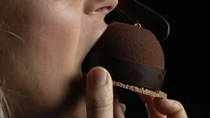 Een foto van de mond van presentatrice Janouk die in een chocoladetaartje bijt, van opzij gezien.