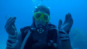 Foto van Freek Vonk met een duikpak aan onder water met zijn armen vragend omhoog.