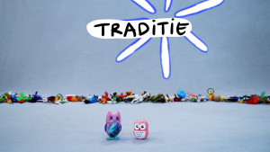 Een foto van een twee kleine speelgoed uilen met daarboven het woord "traditie"