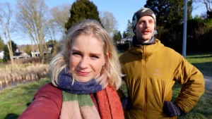 Een selfie van Janouk en Bram, ze staan in een voortuin in de zon, zij heeft een kleurige sjaal om, hij heeft een muts op.